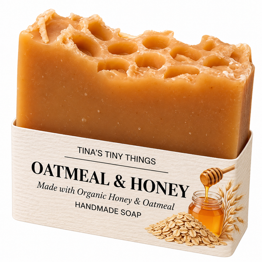 Tina's Tiny Things Oatmeal & Honey Handmade Soap Bar made with organic honey and oatmeal, featuring a golden honey-colored soap with a honeycomb-inspired top and cream packaging decorated with honey, oats, and wheat illustrations.